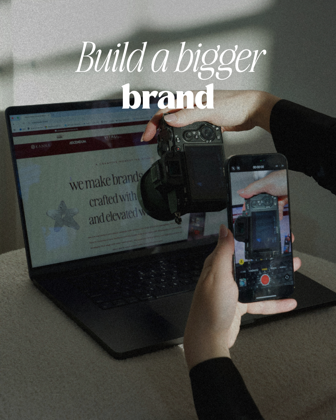 A laptop is in the background with hands using an iPhone to take a picture of a camera that is taking a picture of the laptop. Text says, "Build a bigger brand."